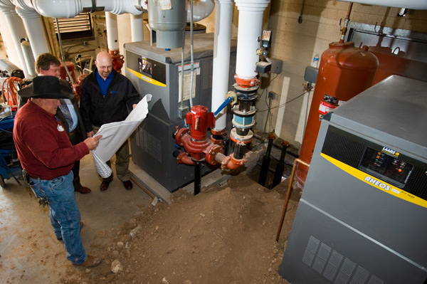 Jim Butler with SFPS General Services Don Swick ECI mechanical engineer and Dave Frederick ECI construction manager compare new boiler installation to design plans at Aspen Community Magnet School