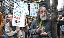 A man holds a plant in his hands surrounded by Earth Day protesters A man holds a plant in his hands surrounded by Earth Day protesters