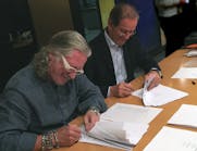 Taco&apos;s John Hazen White, Jr., left, and Elio Marioni of Askoll sign the acquisition agreement documents in Dueville, Italy.