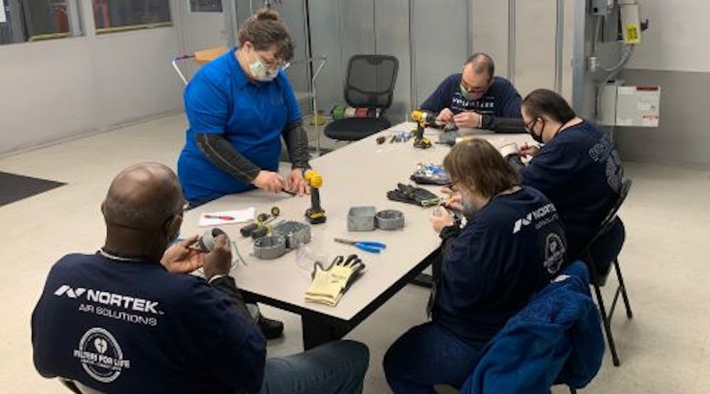 Center for Family Love (CFL) job coach Muffy (standing) oversees air handler light fixture assembly work at Nortek Air Solutions by CFL residents (left to right) Stanley, Jeremy, Dorothy and Maria. (Photo Credit: Nortek Air Solutions)