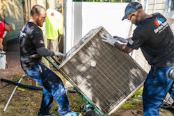 Service Experts team members haul the new HVAC system to the home. Service Experts team members haul the new HVAC system to the home.