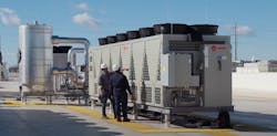Two technicians inspecting a Trane TCAA oil-free magnetic bearing chiller unit on a rooftop at a data center. Two technicians inspecting a Trane TCAA oil-free magnetic bearing chiller unit on a rooftop at a data center.